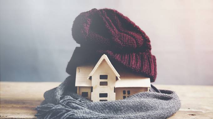 Symbolbild energieeffizientes Heizen © Tiko – stock.adobe.com Symbolbild: Modell eines Holzhauses, das in einer Mütze und einem Schal eingewickelt ist