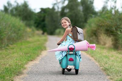 Schulkind auf einem Roller mit Schultüte