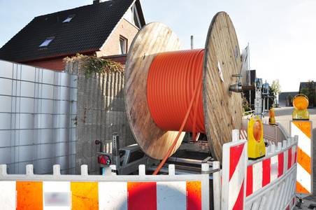 Eine Rolle mit Glasfaser steht auf einer Baustelle vor einem Haus