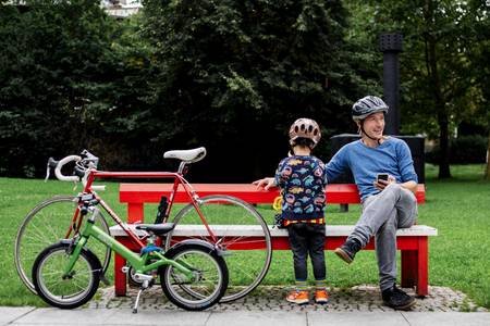 Vater und Kind sitzen auf einer Bank, daneben Fahrräder