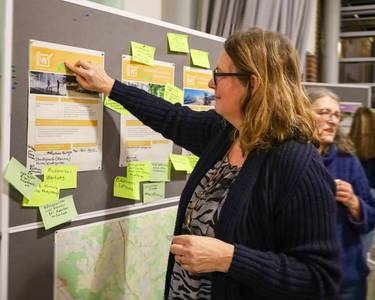 Eine Teilnehmerin klebt einen Punkt auf eine Infowand