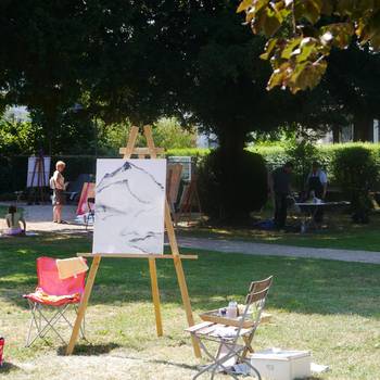 Eine Leinwand mit Bild in Arbeit steht auf einer Wiese