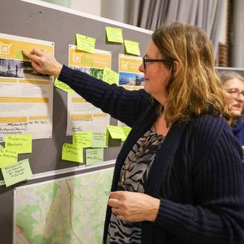 Eine Teilnehmerin klebt einen Punkt auf eine Infowand