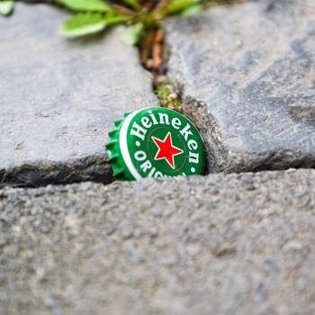 Ein Kronkorken steckt im Kopfsteinpflaster