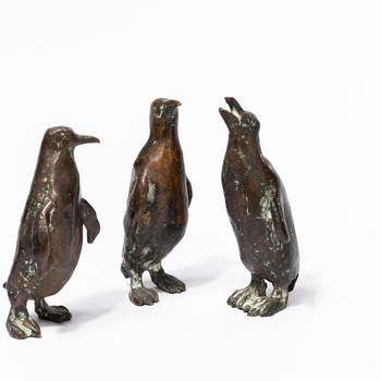Drei Pinguine aus Bronze vor weißem Hintergrund