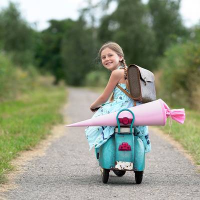 Schulkind auf einem Roller mit Schultüte