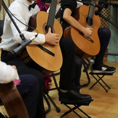 Drei Kinder, die im Anzug Gitarre spielen