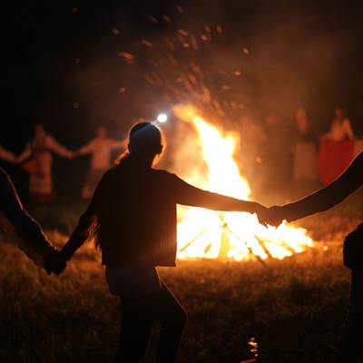 Menschen tanzen um ein großes Feuer