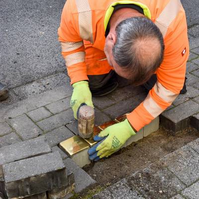 Ein Mitarbeiter des Bauhofes befestigt die Stolpersteine.