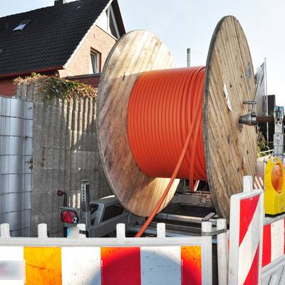 Eine Rolle mit Glasfaser steht auf einer Baustelle vor einem Haus