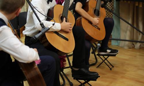 Drei Kinder, die im Anzug Gitarre spielen