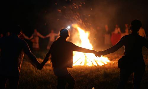 Menschen tanzen um ein großes Feuer