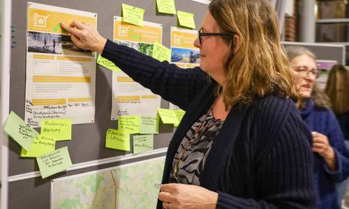 Eine Teilnehmerin klebt einen Punkt auf eine Infowand