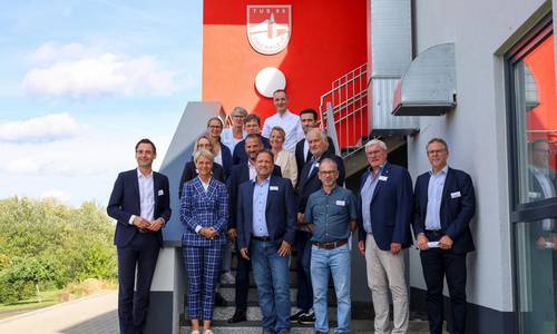 Landrat Sebastian Schuster (2.v.r.), Bürgermeister Lutz Wagner (8.v.r.), Schulleiterin Alexandra Weber (14.v.r.) und Michael Weber (TuS 05 Oberpleis, 9.v.r.), zusammen mit Ministerin Dorothee Feller (13 v.r.) mit allen Teilnehmenden des Besuches in Oberpleis.