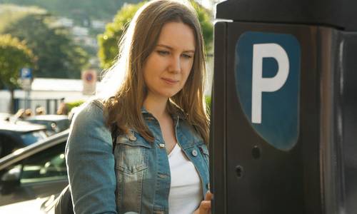 Eine Frau steht vor einem Parkautomaten