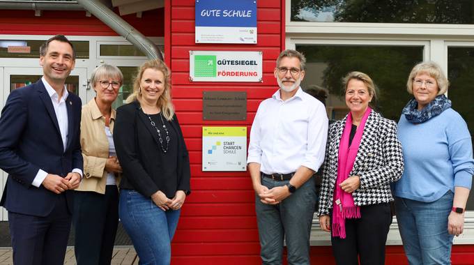 Die Gruppe steht vor der Plakette an der Grundschule