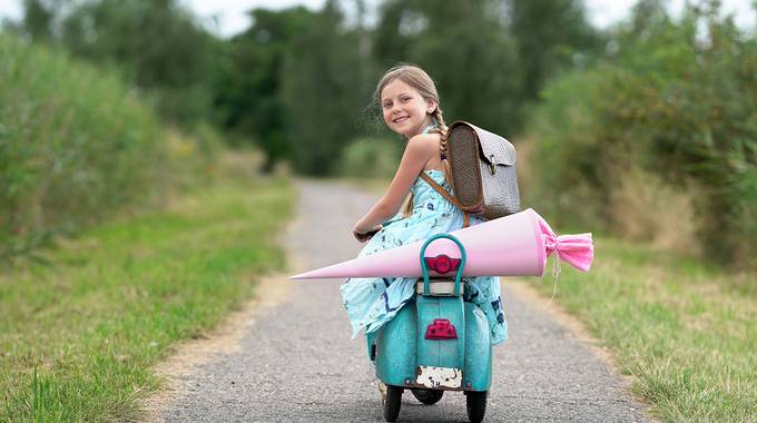 Schulkind auf einem Roller mit Schultüte