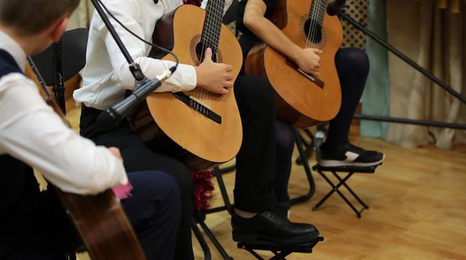 Drei Kinder, die im Anzug Gitarre spielen