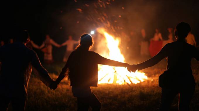 Menschen tanzen um ein großes Feuer