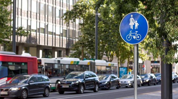 Ein Schild mit Fußgänger- und Radfahrerweg, Im Hintergrund eine Bus- und Autoschlange