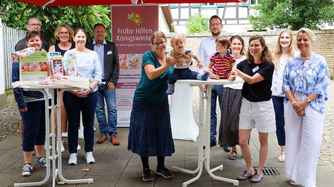 Gruppenbild aller Beteiligten. Die beiden Babies sitzen fröhlich auf dem Tisch