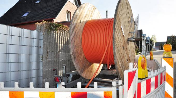 Eine Rolle mit Glasfaser steht auf einer Baustelle vor einem Haus