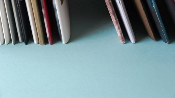 Rückseiten von Heften, aufgereiht auf blauem Untergrund