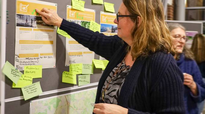 Eine Teilnehmerin klebt einen Punkt auf eine Infowand