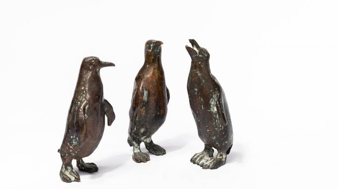 Drei Pinguine aus Bronze vor weißem Hintergrund