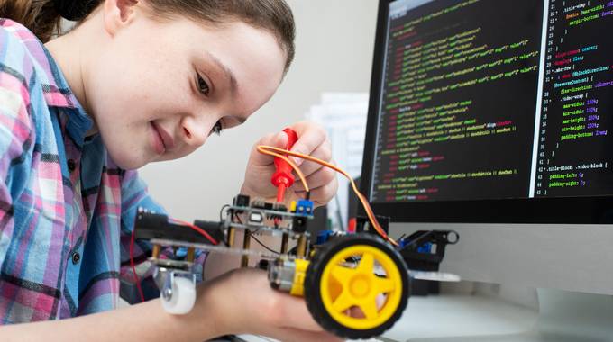 Mädchen baut und programmiert einem Roboter